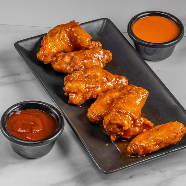 Six Flaming Hot Halal Grill chicken wings coated in orange sauce, with two small sauce cups.