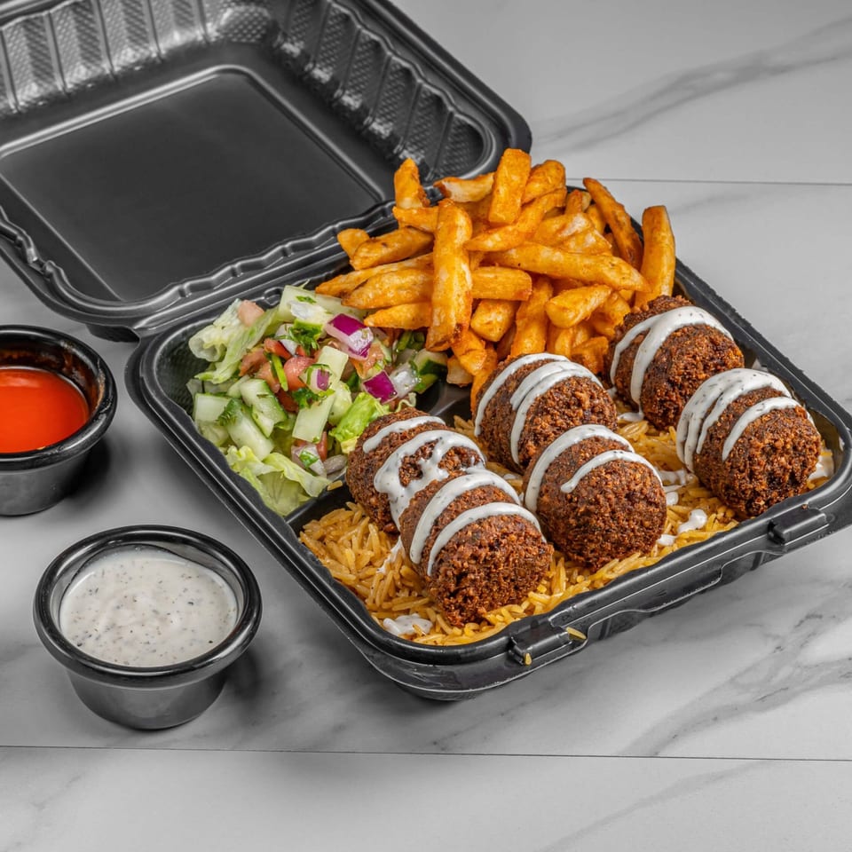 Halal falafel platter with rice, fries, salad, and sauces in a black takeout container.