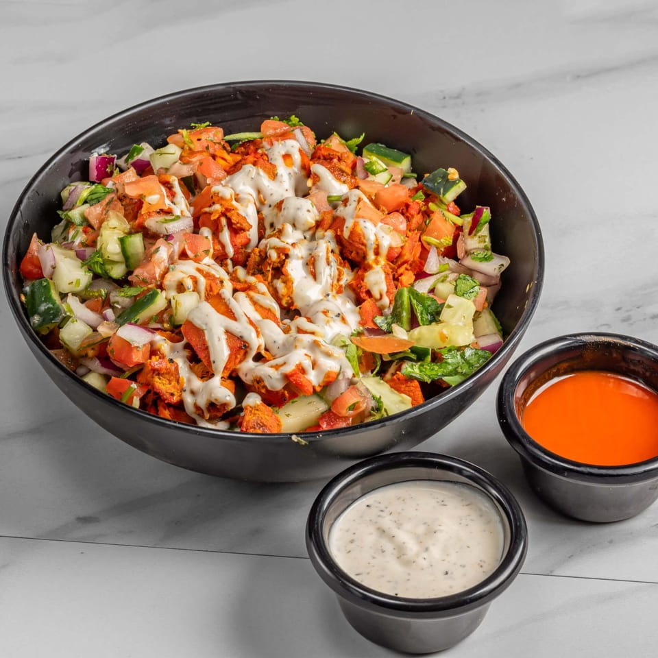 Halal chicken salad with white sauce, diced tomatoes, cucumbers, and onions, with two side sauces.